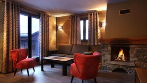 A cozy living room with a stone fireplace, two red armchairs, a sofa, and a coffee table. - Wifi, fitness, swimming pool, sauna, hammam, balcony, tv, ski locker, 72m², Les Arcs (Les Arcs)