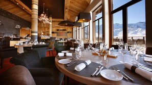 Un restaurante con vistas a la montaña, interior de madera e iluminación moderna.