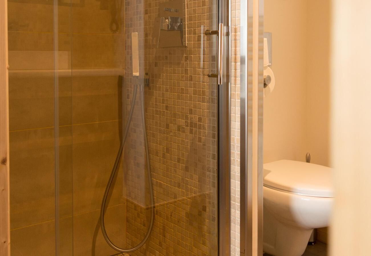 Une salle de bain avec une douche à parois de verre, un mur carrelé et des toilettes.