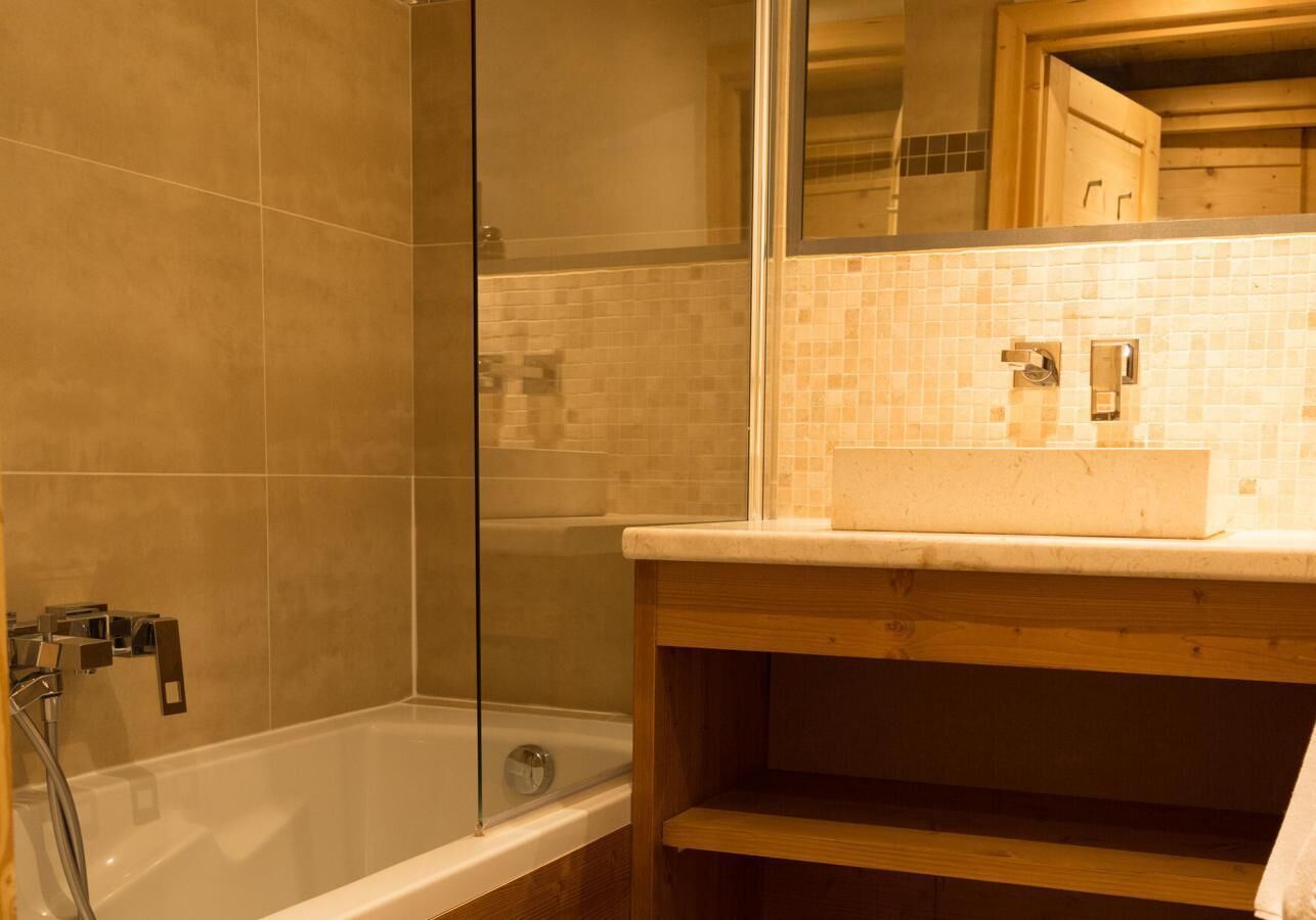 Un baño con cabina de ducha de vidrio, bañera y tocador de madera con lavamanos.