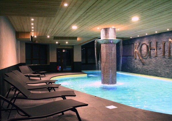A swimming pool with lounge chairs and a water feature.