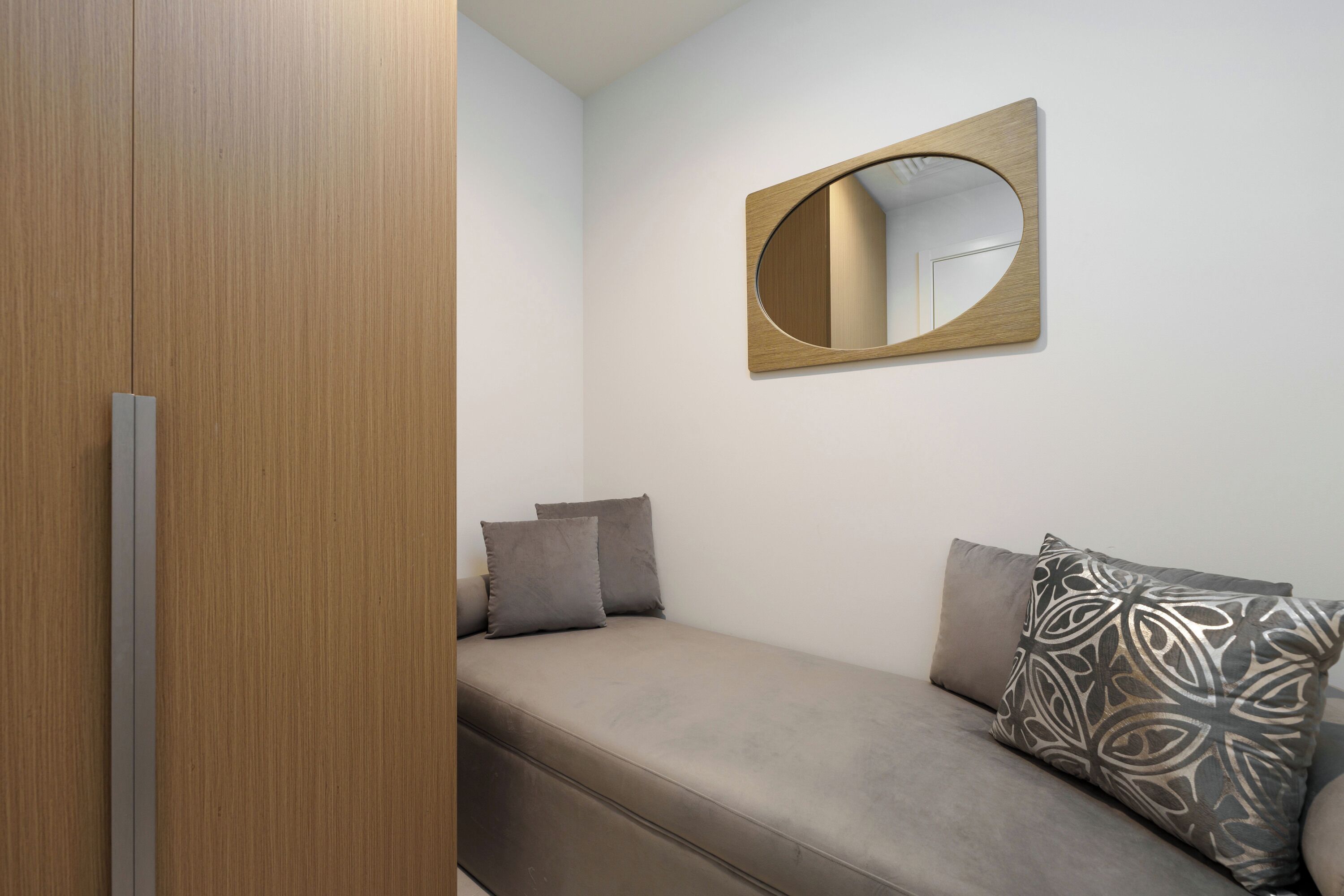 Un dormitorio con cama, un armario de madera y un espejo fijado a la pared.