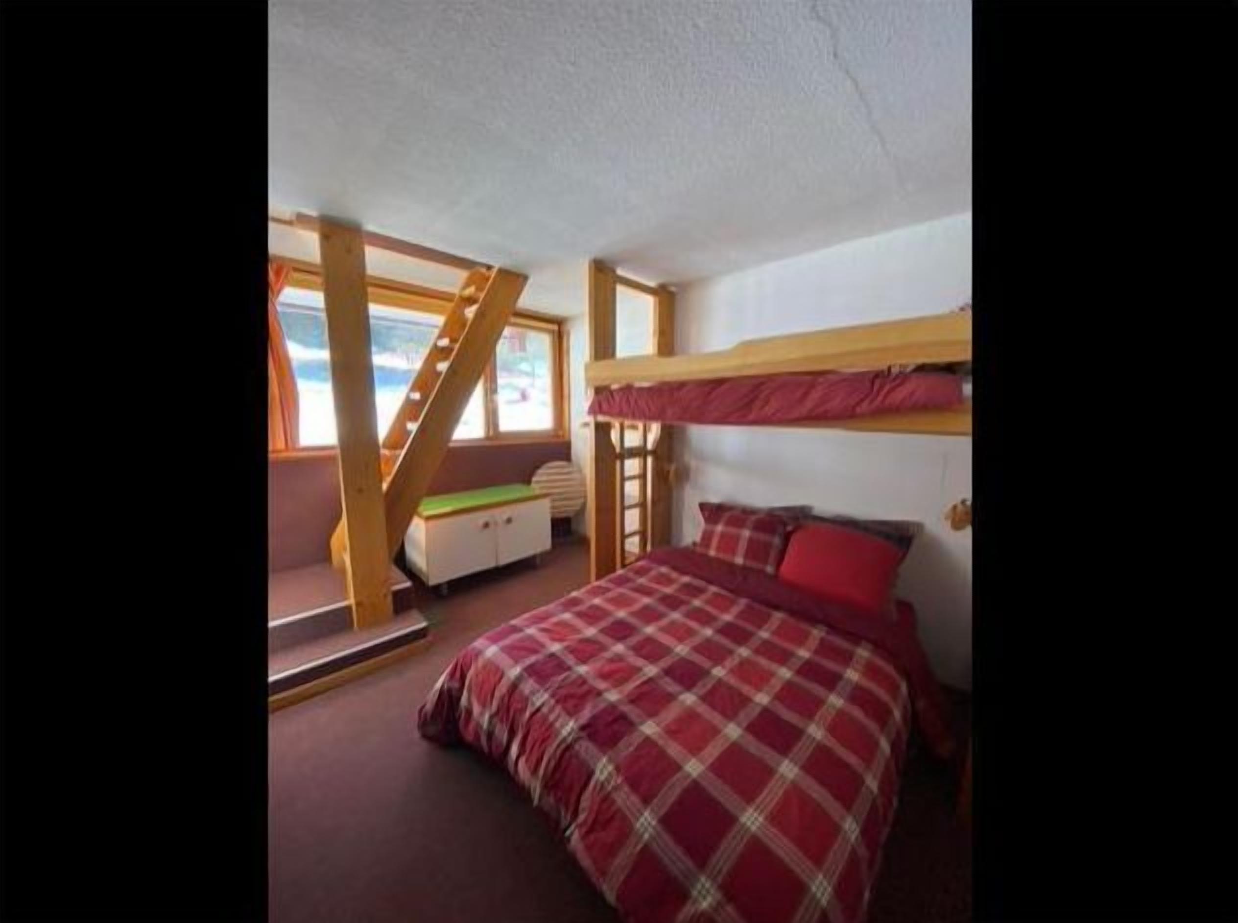 Ein Schlafzimmer mit Etagenbett, Schreibtisch und Fenster.