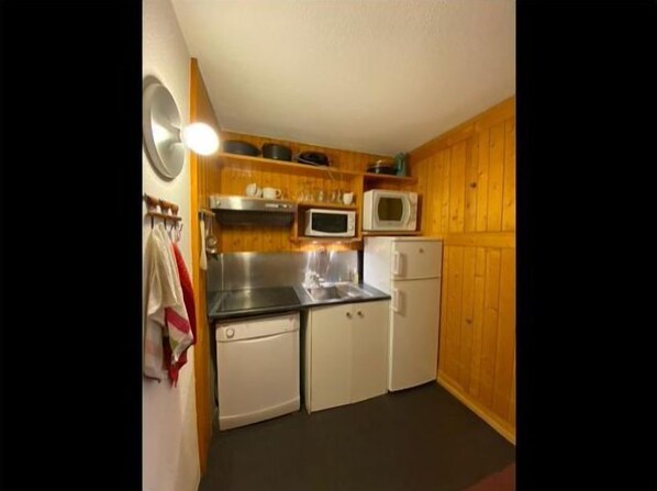 A compact kitchen with a microwave, stove, and refrigerator.