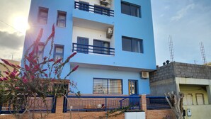 A multi-story building with a blue facade, multiple balconies, and a brick lower level. - Txada Hostel (Praia)