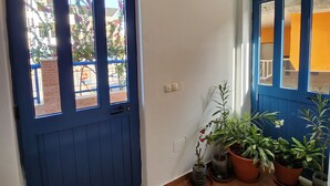 A blue door with a window, a tiled floor, and several potted plants. - Txada Hostel (Praia)