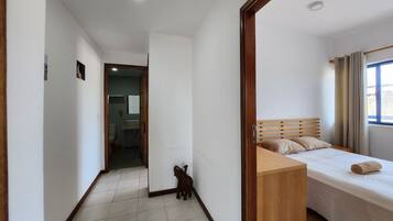 A bedroom with a bed, wooden headboard, and a window with curtains.
