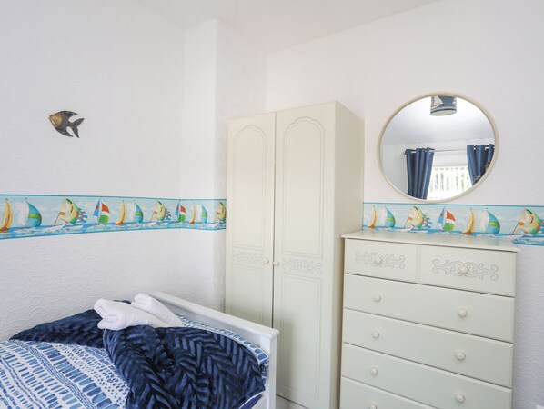 A bedroom with a bed, a dresser, a wardrobe, and a mirror. - Morlais (Ty Croes)