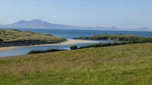 A coastal landscape with a beach, grassy areas, and a body of water. - Morlais (Ty Croes)