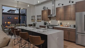 A modern kitchen with a large island, bar stools, and a view of the cityscape.