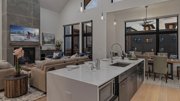 A modern kitchen with a central island, a dining area with a view, and a cozy living space with a fireplace.