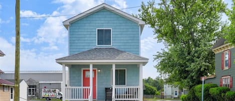 A two-story house with a red door and white porch.