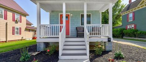 A two-story house with a front porch, a red door, and a number 6265 on the front steps.