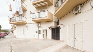 Un immeuble résidentiel à plusieurs étages, doté de balcons, d’une porte de garage et d’un appareil de climatisation.