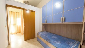 Une chambre à coucher comprenant un lit, une armoire et une porte donnant sur une autre pièce.