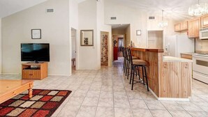 A modern living room with a TV, a wooden coffee table, and a patterned rug. - Seashell Memories (Rockport)