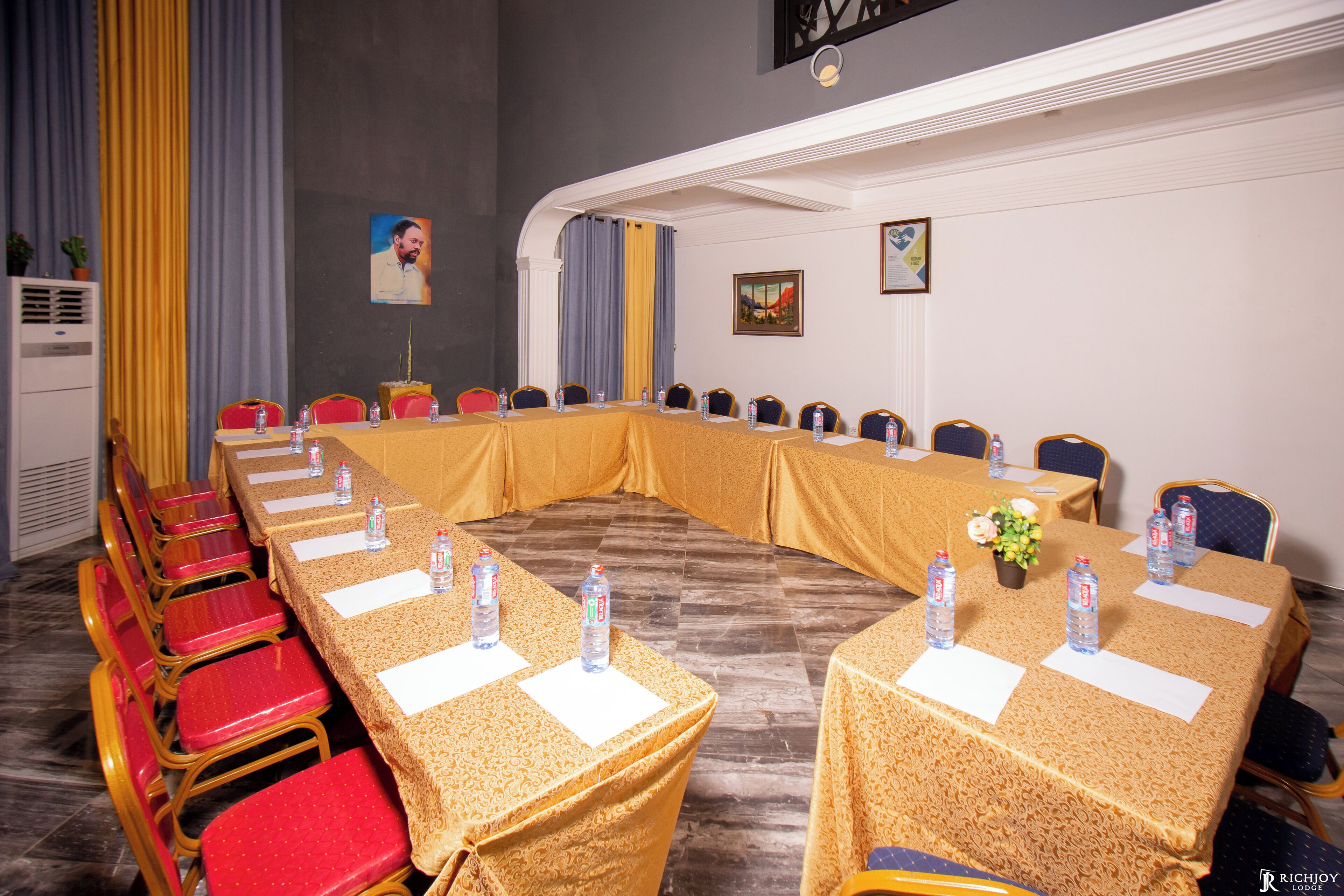A conference room with a long table, red chairs, and water bottles on the table.
