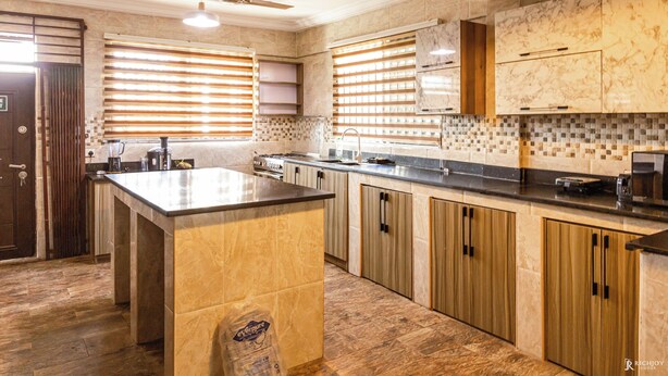 Una cocina moderna con una isla de mármol, armarios de madera y un salpicadero de azulejos.