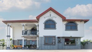 Un edificio de dos pisos con techo rojo, un balcón y un letrero que dice 'RICHIJONG LODGE'.
