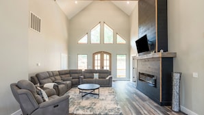 A spacious living room with a sectional sofa, a fireplace, and large windows.