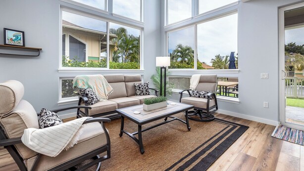 Een ruime woonkamer met grote ramen, een zithoek, een salontafel en uitzicht op het omliggende landschap.