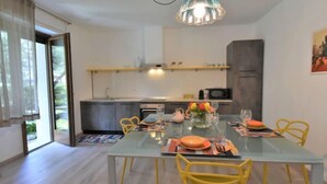 A modern dining area with a glass table, yellow chairs, and a hanging light fixture.
