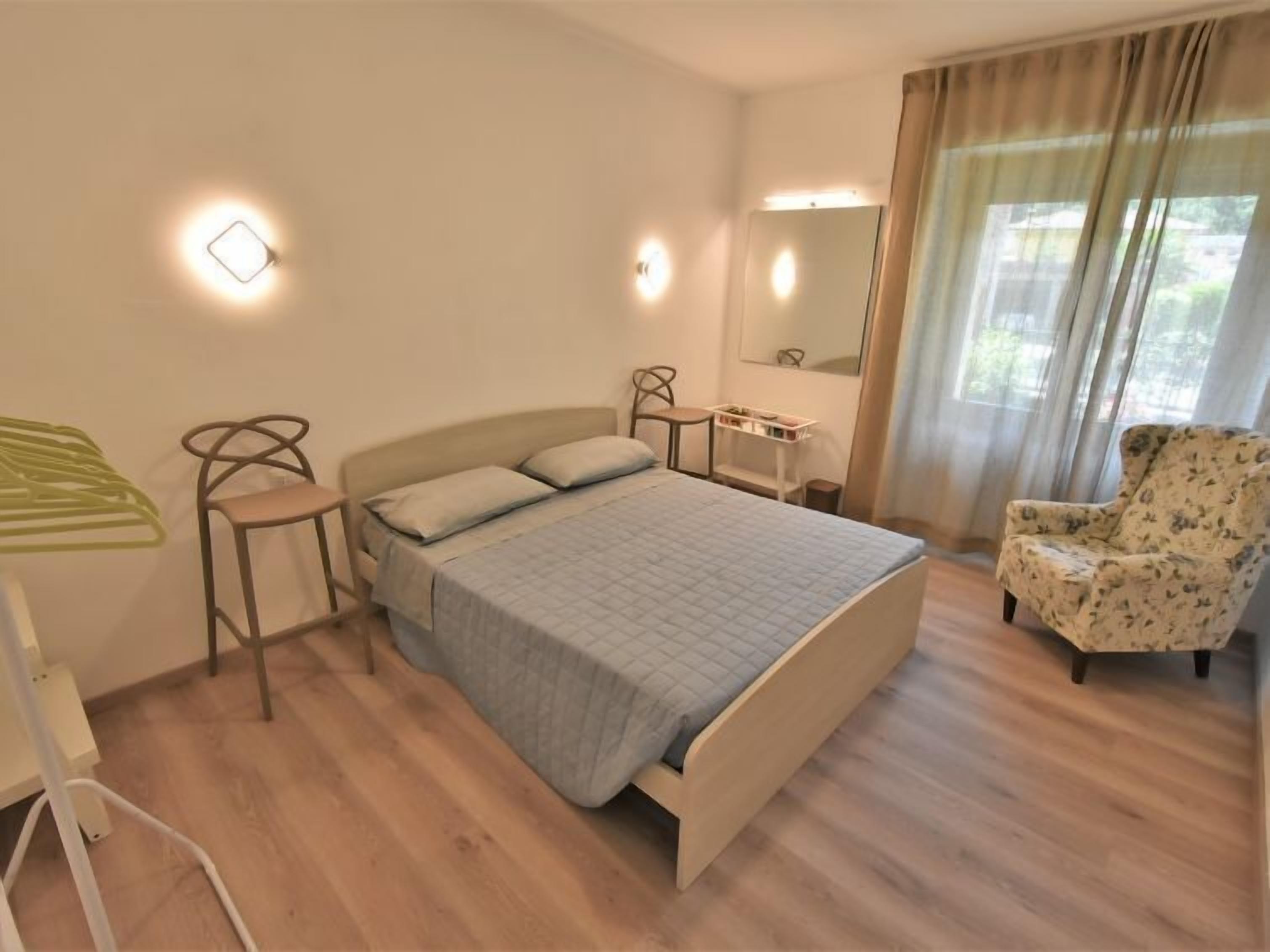 Een slaapkamer met een bed, een stoel, een bureau en een spiegel.