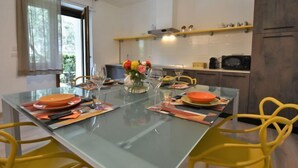 A modern dining area with a glass table, yellow chairs, and a vase of flowers.