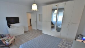 A bedroom with a large bed, a dresser, a TV, and a wardrobe.