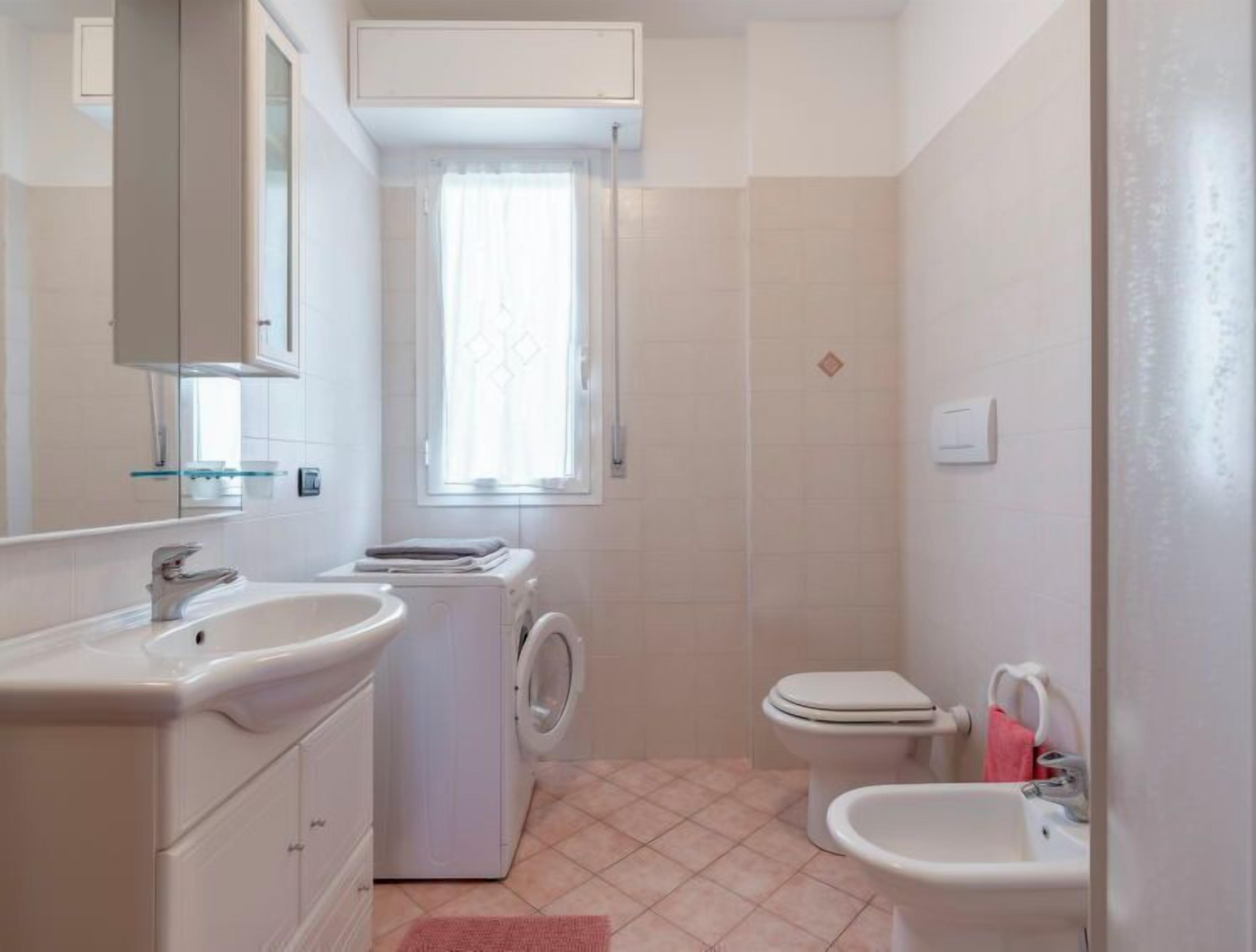 A compact bathroom with a sink, toilet, and washing machine.