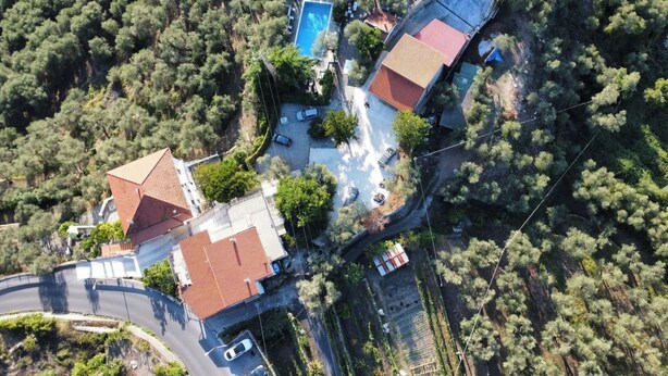 An aerial view of a residential area with multiple buildings, a swimming pool, and a curved road. - Apartment Mimosa by Interhome (Chiusanico)