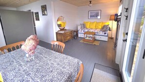 Een gezellige woonkamer met een bank, een houten tafel en een eettafel met een tafelkleed met een patroon.