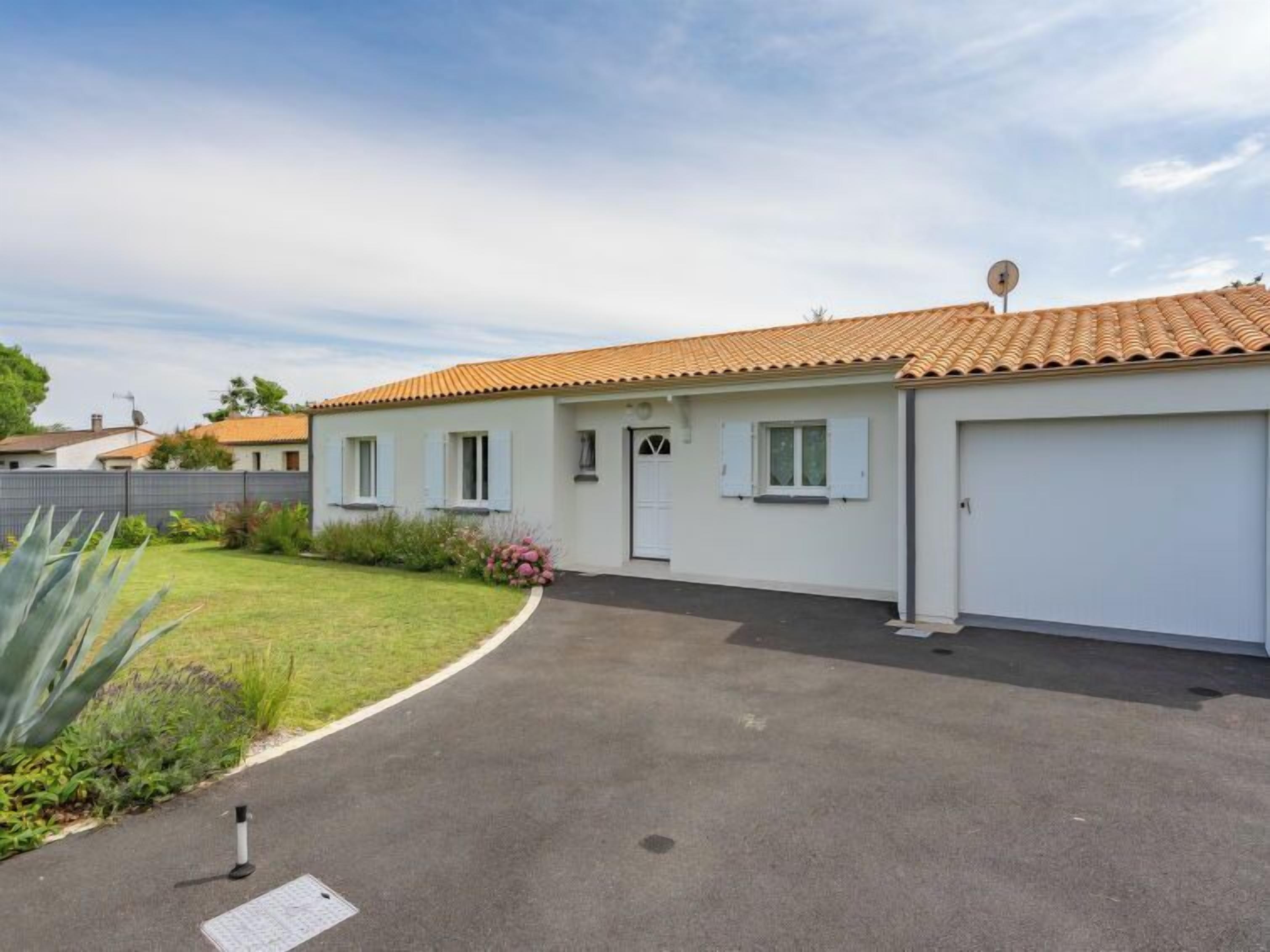 A single-story house with a tiled roof, a front garage, and a well-maintained lawn.