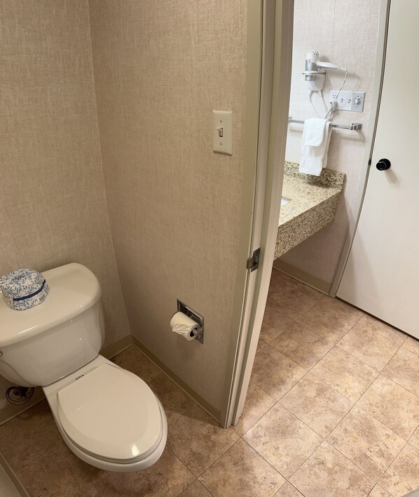 A bathroom with a toilet, a paper towel dispenser, and a towel rack.