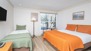 A bedroom with two beds, a desk, a chair, a lamp, and a window with a view of trees. - Mountainside Inn 109 1 Bedroom Hotel Room by Alpine Lodging Telluride (Telluride)