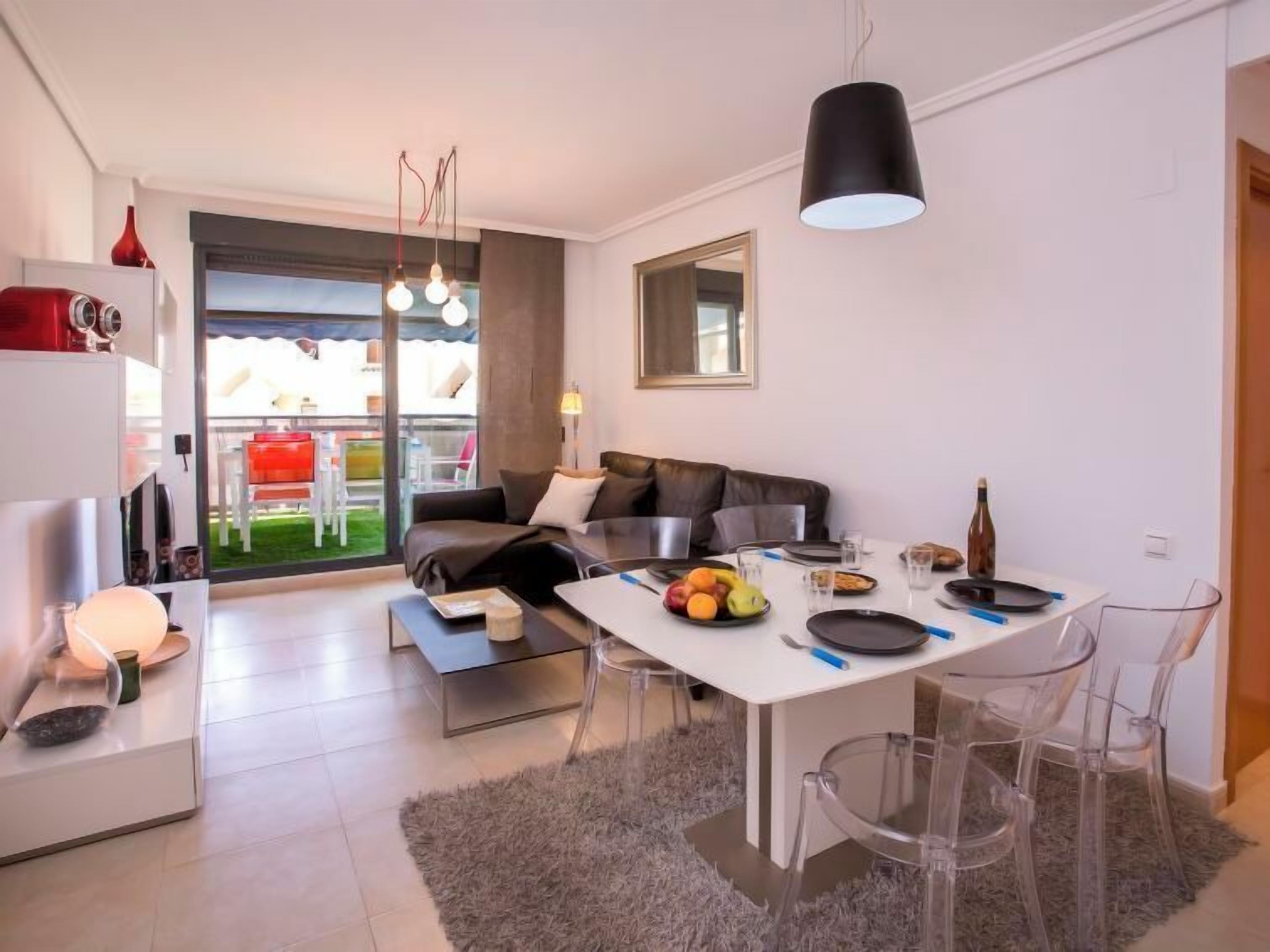A modern living space with a dining area, a sofa, and a kitchen.