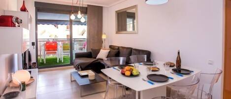A modern living space with a dining area, a sofa, and a kitchen.