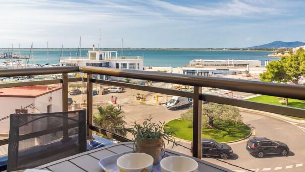A balcony with a view of a marina, a road, and a parking lot.