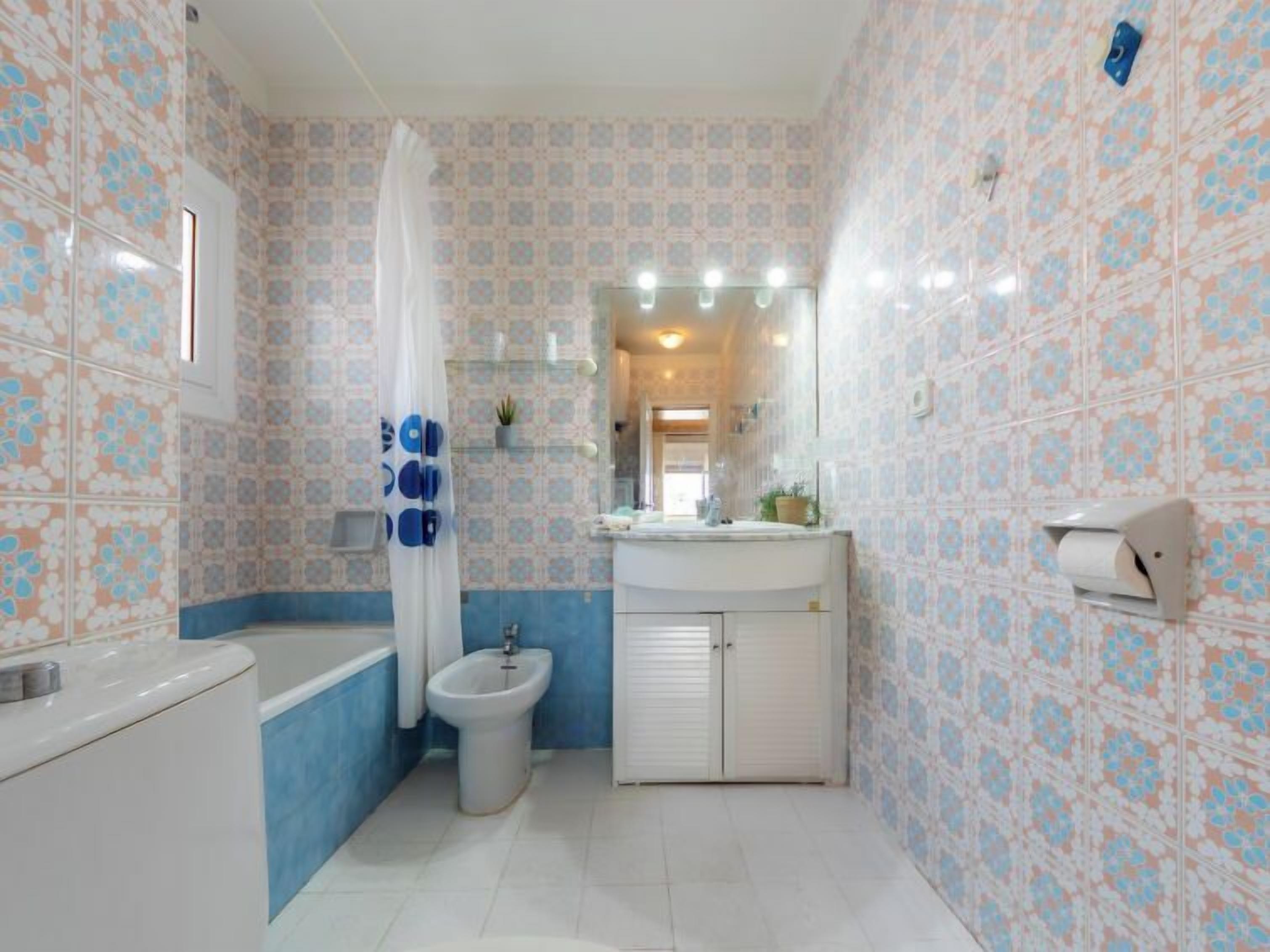 Een badkamer met een bad, een toilet, een wastafel en een hygiëneschuiver.