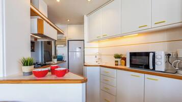 Een koelkast, een magnetron, een oven, kookgerei, borden en bestek