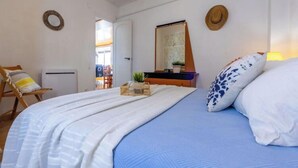 A bedroom with a bed, a chair, a mirror, and a door leading to another room.