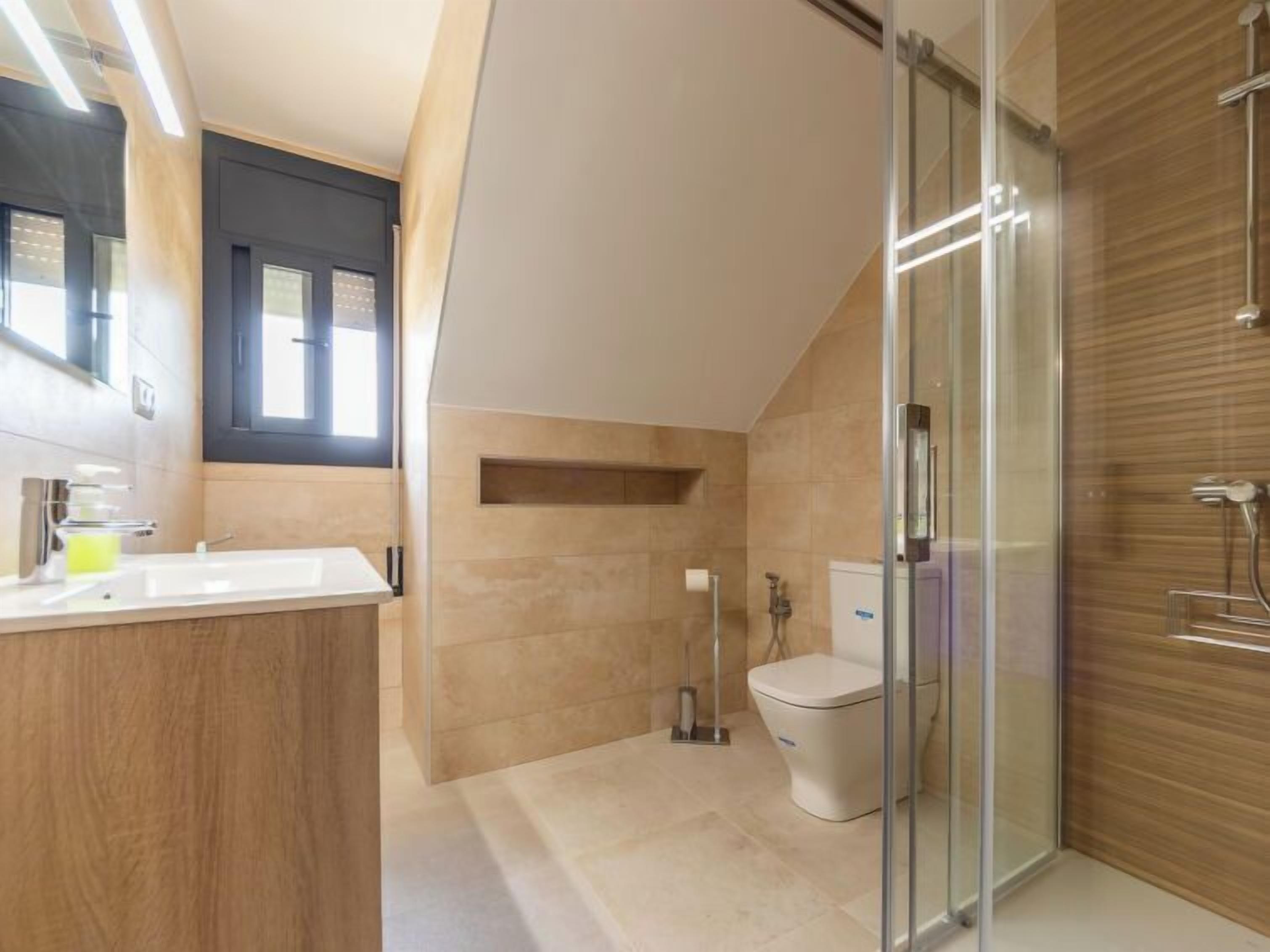 A modern bathroom with a shower, toilet, and sink.
