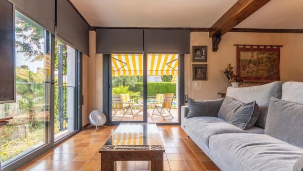 Un salon moderne doté d’une grande porte-fenêtre coulissante donnant sur un espace patio extérieur.