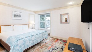 A hotel room with a bed, a small table, a TV, a window, and a door. - Mountainside Inn 122 1 Bedroom Condo by Alpine Lodging Telluride (Telluride)