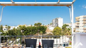 A balcony with a table set for two, overlooking a cityscape with buildings and trees. - Apartment Velez by Interhome (Nerja)