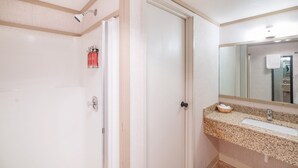 Een badkamer met een witte deur, een wastafel met een granieten aanrechtblad en een spiegel boven de wastafel.