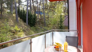 A balcony with a table set for two, featuring a bottle, a glass, and a bowl of fruit. - Sonnenküste by Interhome (Trassenheide)