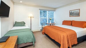 A bedroom with two beds, a desk, a chair, a TV, and a window with a view of trees. - Mountainside Inn 409 1 Bedroom Hotel Room by Alpine Lodging Telluride (Telluride)