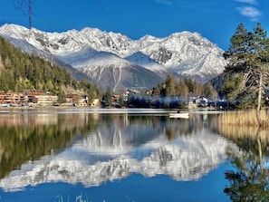 A mountain resort with a lake, reflecting the mountains and buildings.