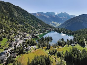 A mountain village with a lake, surrounded by forested hills and mountains.